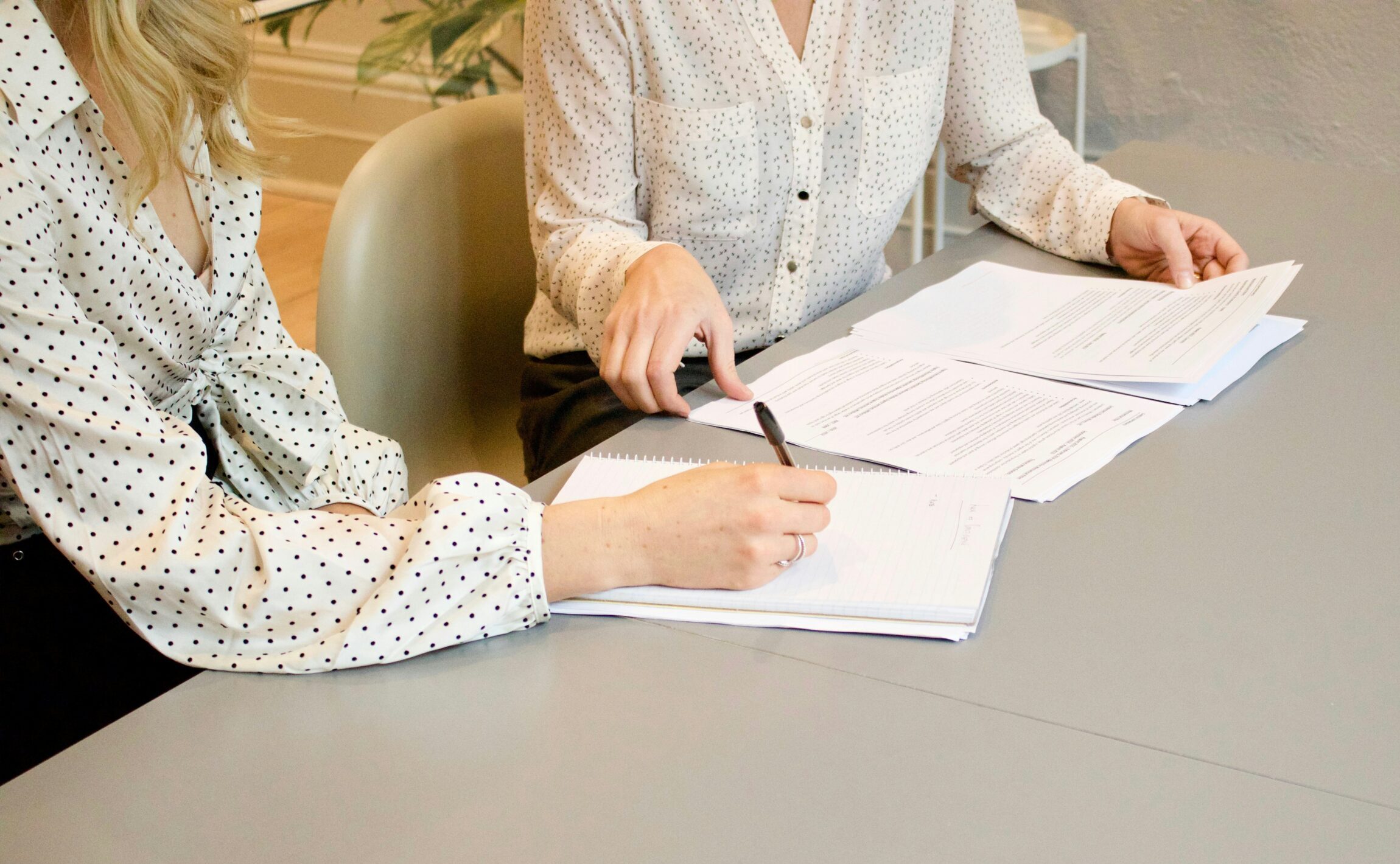Dos mujeres revisando documentos y tomando notas en un despecho de abogados